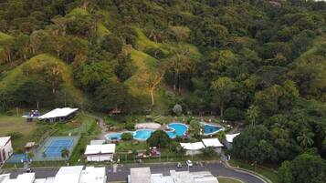 A resort with multiple swimming pools, tennis courts, and a lush green landscape.