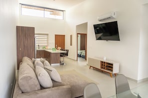 A modern living room with a sofa, a glass coffee table, and a TV mounted on the wall. - Casa Kyma Playa Herradura (Herradura)