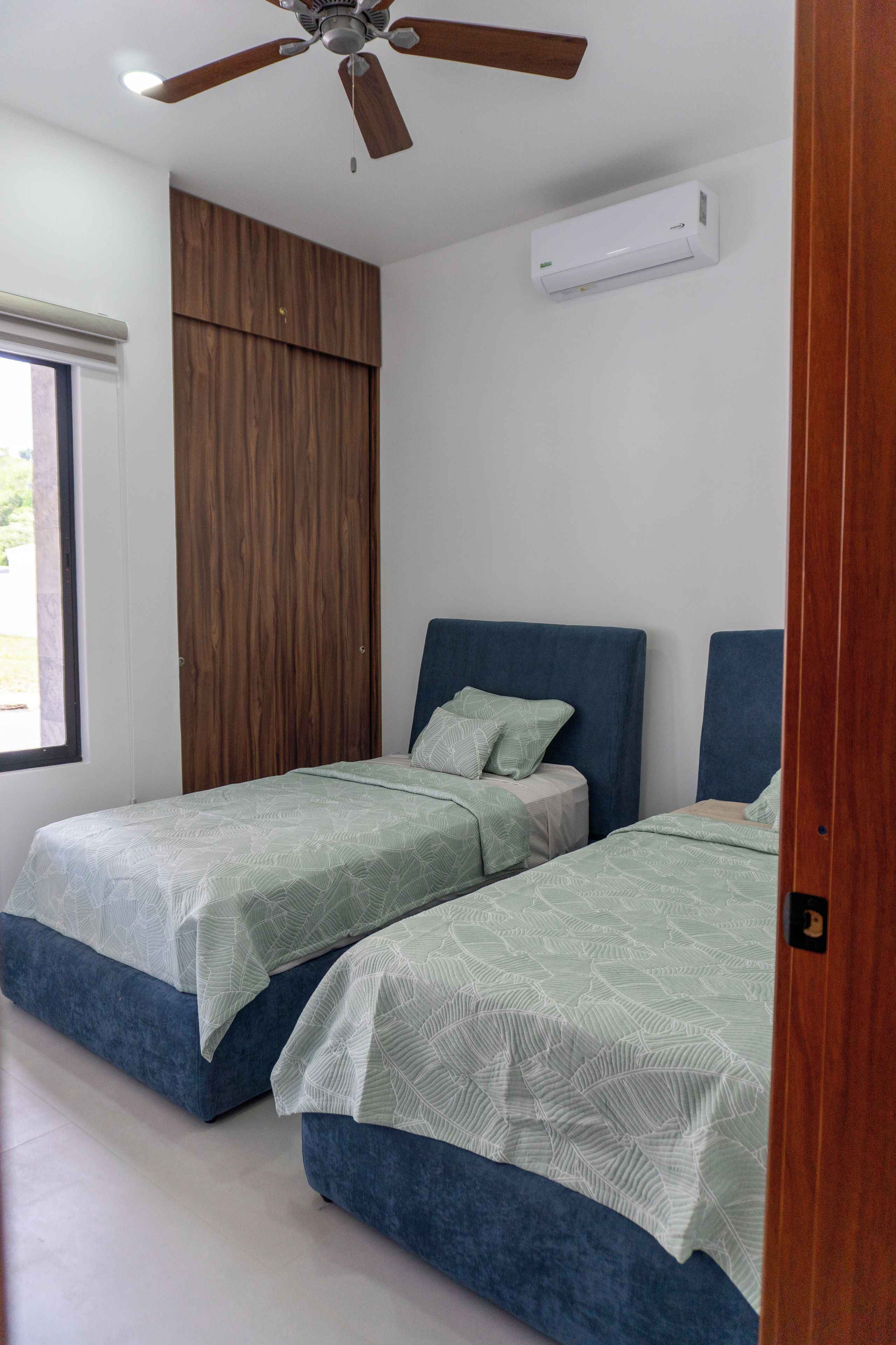Une chambre avec deux lits, un ventilateur de plafond et un appareil de climatisation.