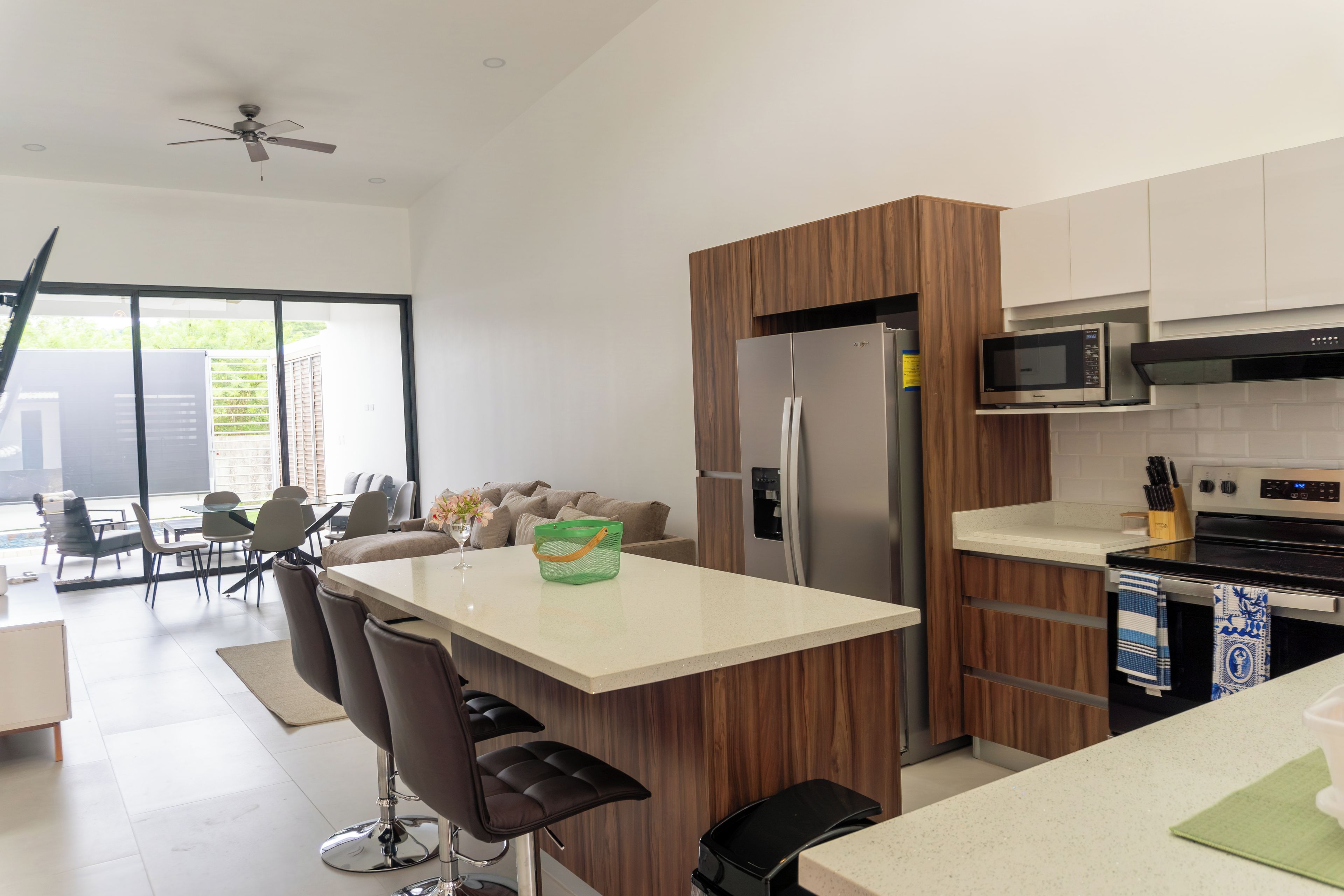 A modern kitchen with a central island, stainless steel appliances, and a dining area with a view.