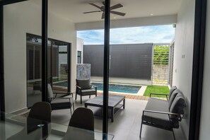 A modern interior with a glass door leading to a pool area. - Casa Kyma Playa Herradura (Herradura)