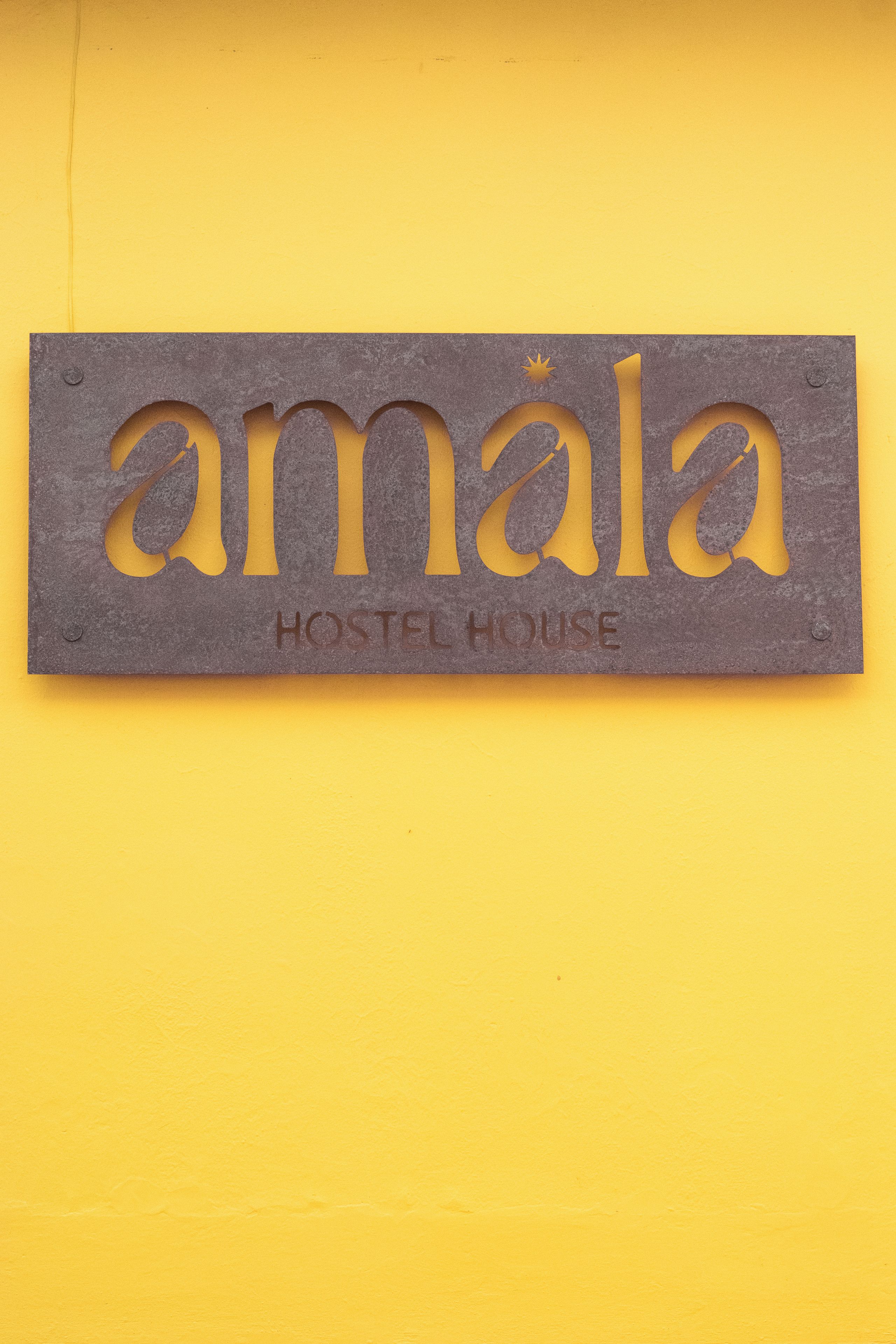 Une enseigne indiquant un hôtel pour jeunes, avec le nom « Amala » et les mots « HÔTEL POUR JEUNES » en dessous.