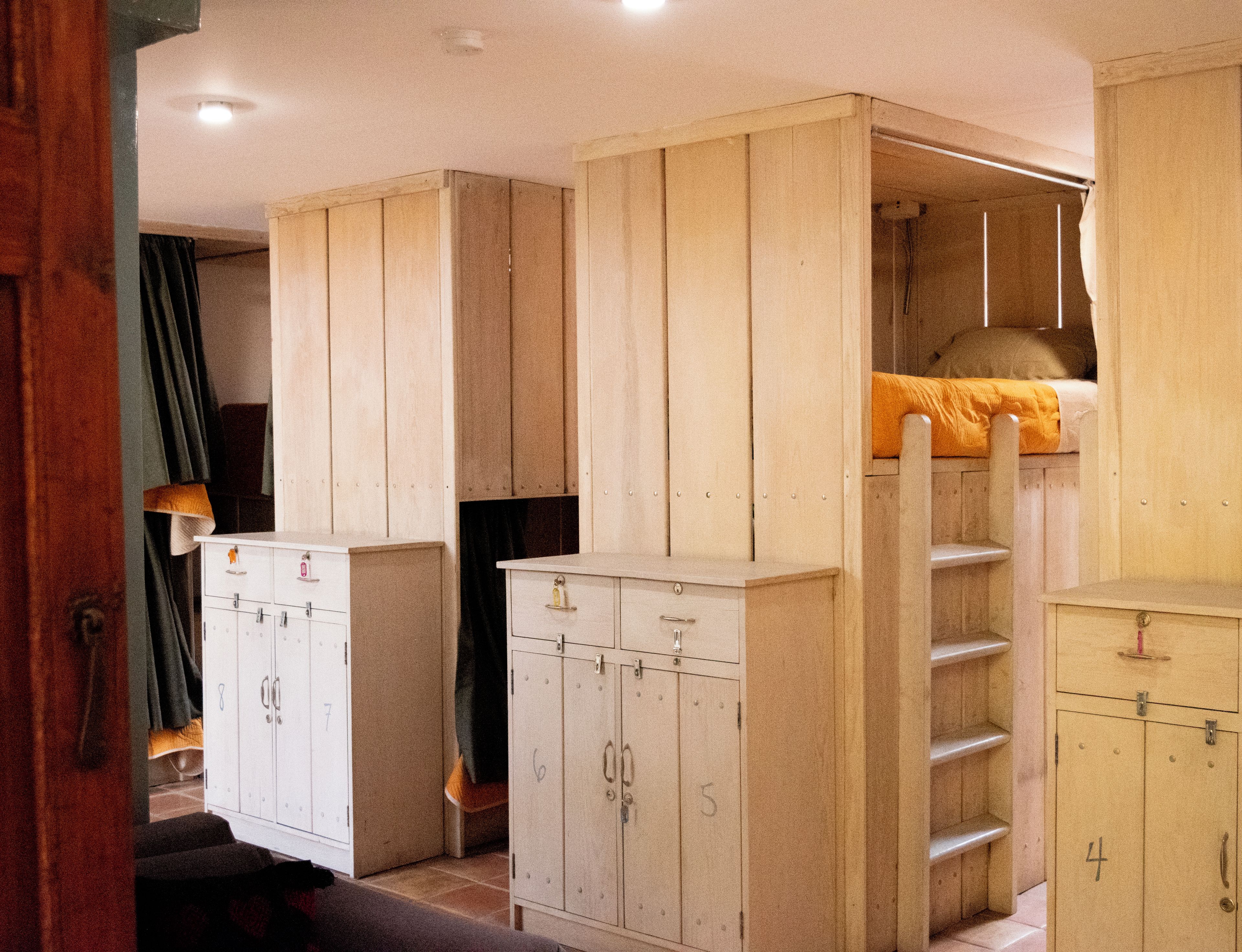 Ein Zimmer mit Etagenbetten, Holzschränken und einer Hockerleiter.