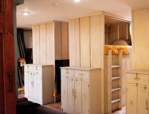 Una habitación con literas, armarios de madera y una escalera.