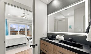 Ein modernes Badezimmer mit einem großen Spiegel, zwei Waschbecken und einem Deckenventilator.