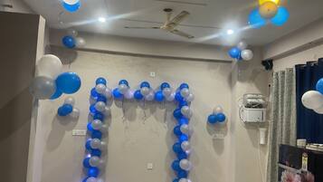 A room with a ceiling fan, a wall-mounted air conditioner, and a decorative balloon arch.