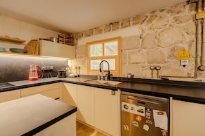 A kitchen with a stone wall, a window, and a dishwasher. - The magic of the stone hause,withheated and cooled pool&peaceful escape (İzmir)