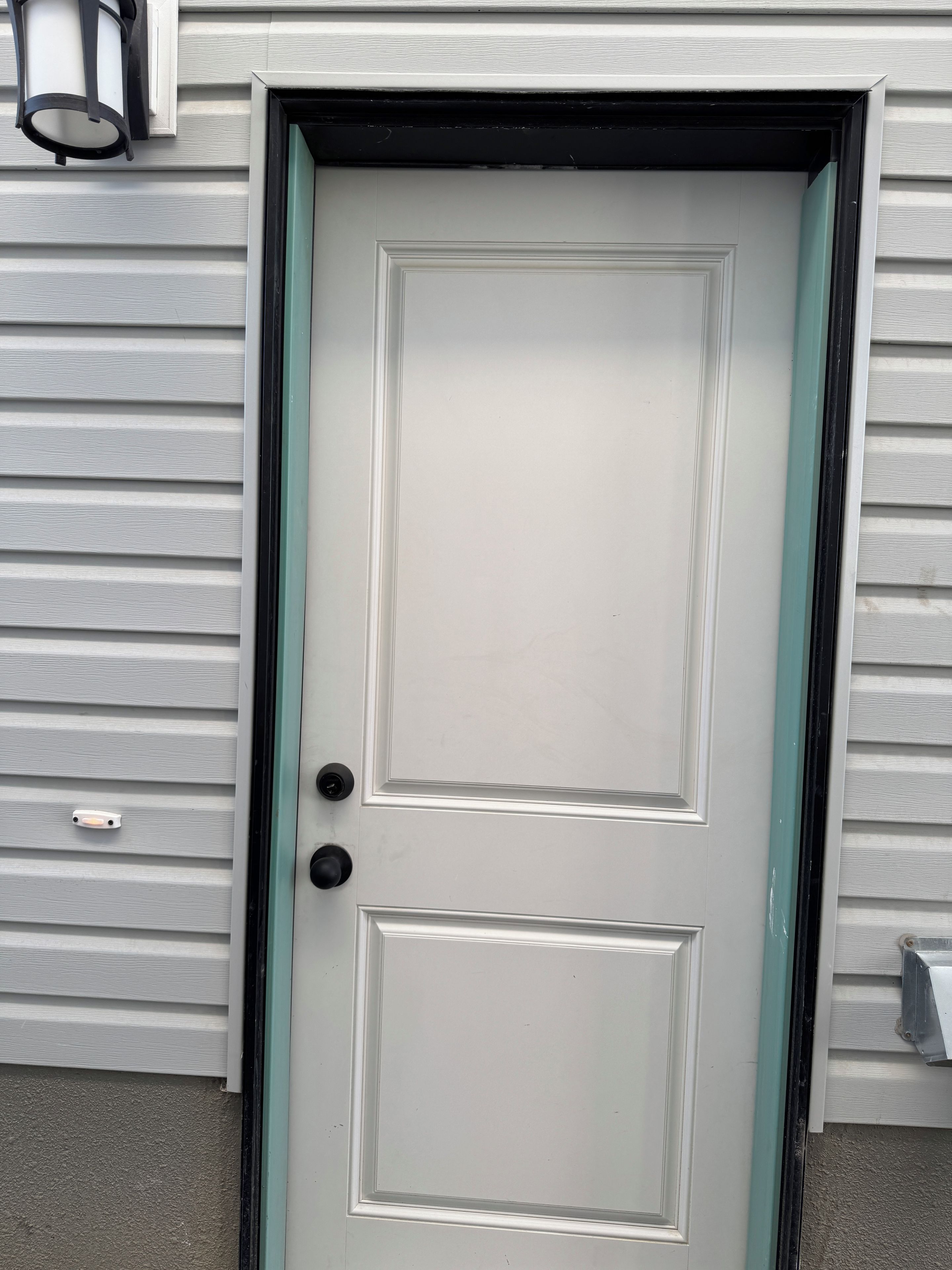 A white door with a black handle and a green trim.