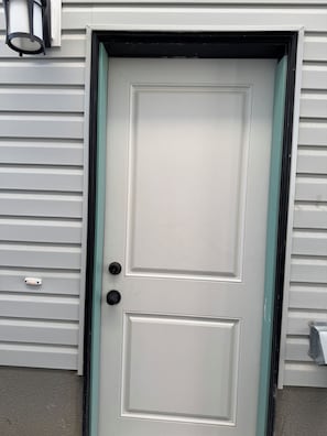 Une porte blanche avec une poignée noire et un cadre vert.