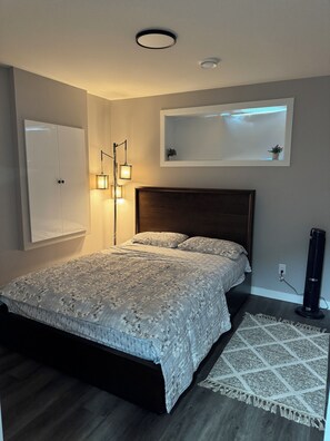 Een slaapkamer met een bed, nachtlampen, een wandplank en een ventilator.
