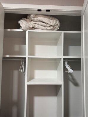 Un placard blanc avec plusieurs étagères et un espace pour suspendre les vêtements.