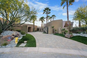 A landscaped entrance with palm trees, a fire hydrant, and a paved pathway leading to a building. - Stunning 9 Bedroom Golf Estate - 200 Feet Golf Frontage on Private Course (Rancho Mirage)
