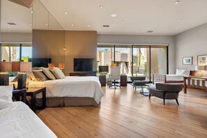 A modern hotel room with a large bed, a desk, a TV, and a view of the outdoors. - Stunning 9 Bedroom Golf Estate - 200 Feet Golf Frontage on Private Course (Rancho Mirage)