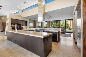 A modern kitchen with a large island, built-in appliances, and a view to the outdoors. - Stunning 9 Bedroom Golf Estate - 200 Feet Golf Frontage on Private Course (Rancho Mirage)