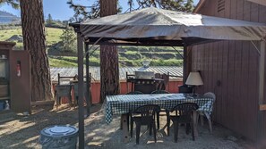 An outdoor patio area with a table and chairs, a grill, and a covered seating area. - The Apple Place Room #2 (Miramonte)