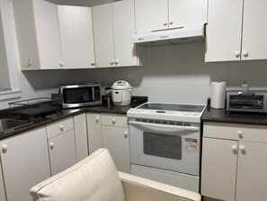 A kitchen with white cabinets, a microwave, a toaster, and a stove.