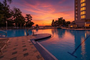 A swimming pool with a sunset view, lounge chairs, and a building with multiple windows. - 12 Floors Up with King, Bunks and Resort Pool (Orlando)