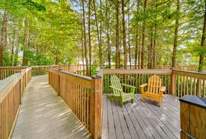 A wooden deck with a wooden railing, a green Adirondack chair, and a wooden bench. - 12 Floors Up with King, Bunks and Resort Pool (Orlando)
