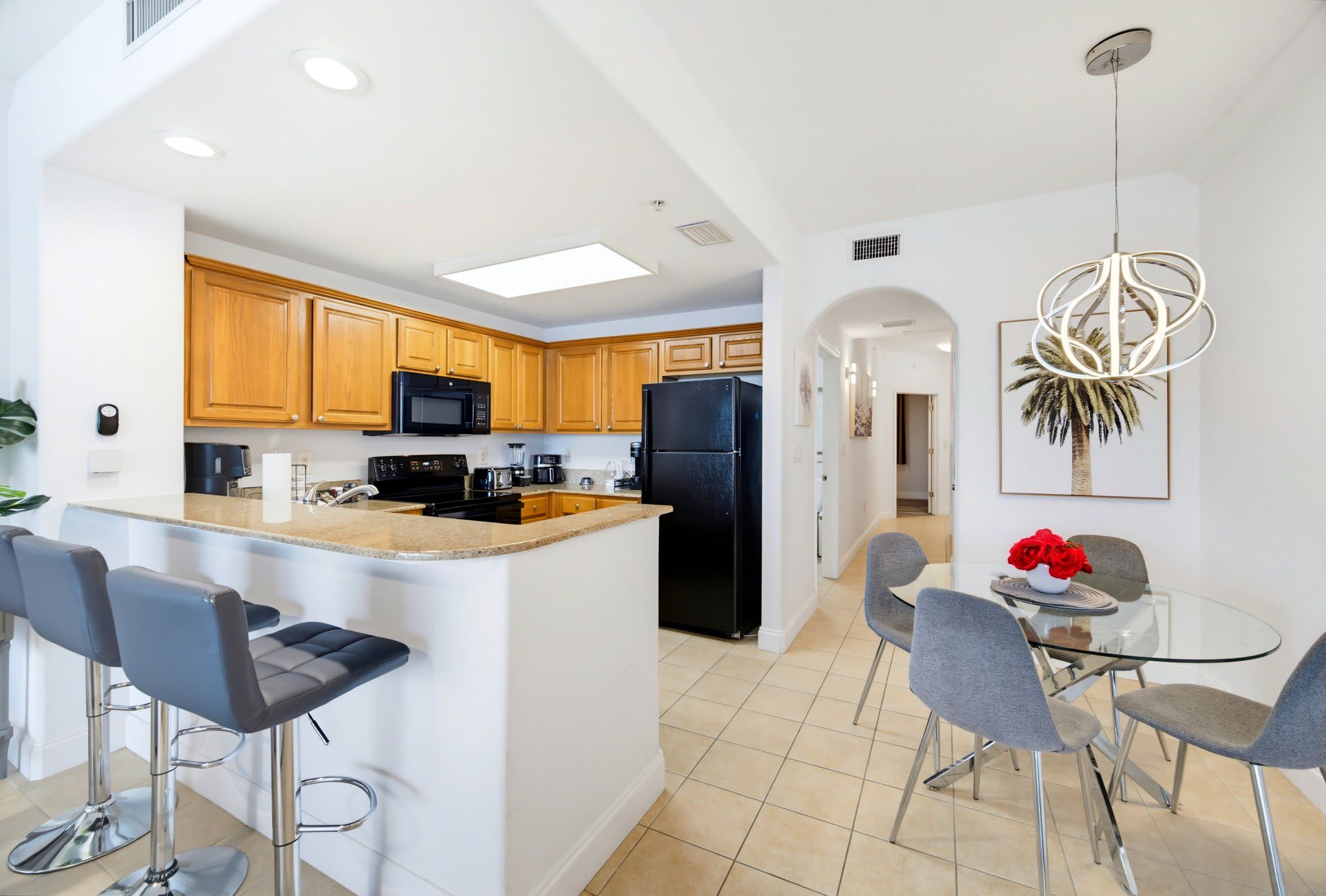 A modern kitchen with wooden cabinets, a black refrigerator, and a central island with bar stools.