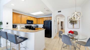 A modern kitchen with wooden cabinets, a black refrigerator, and a central island with bar stools.