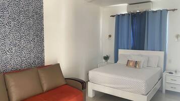 Un dormitorio con cama, mesita de noche, luz de pared y ventilador de techo, además de una pared con diseño.