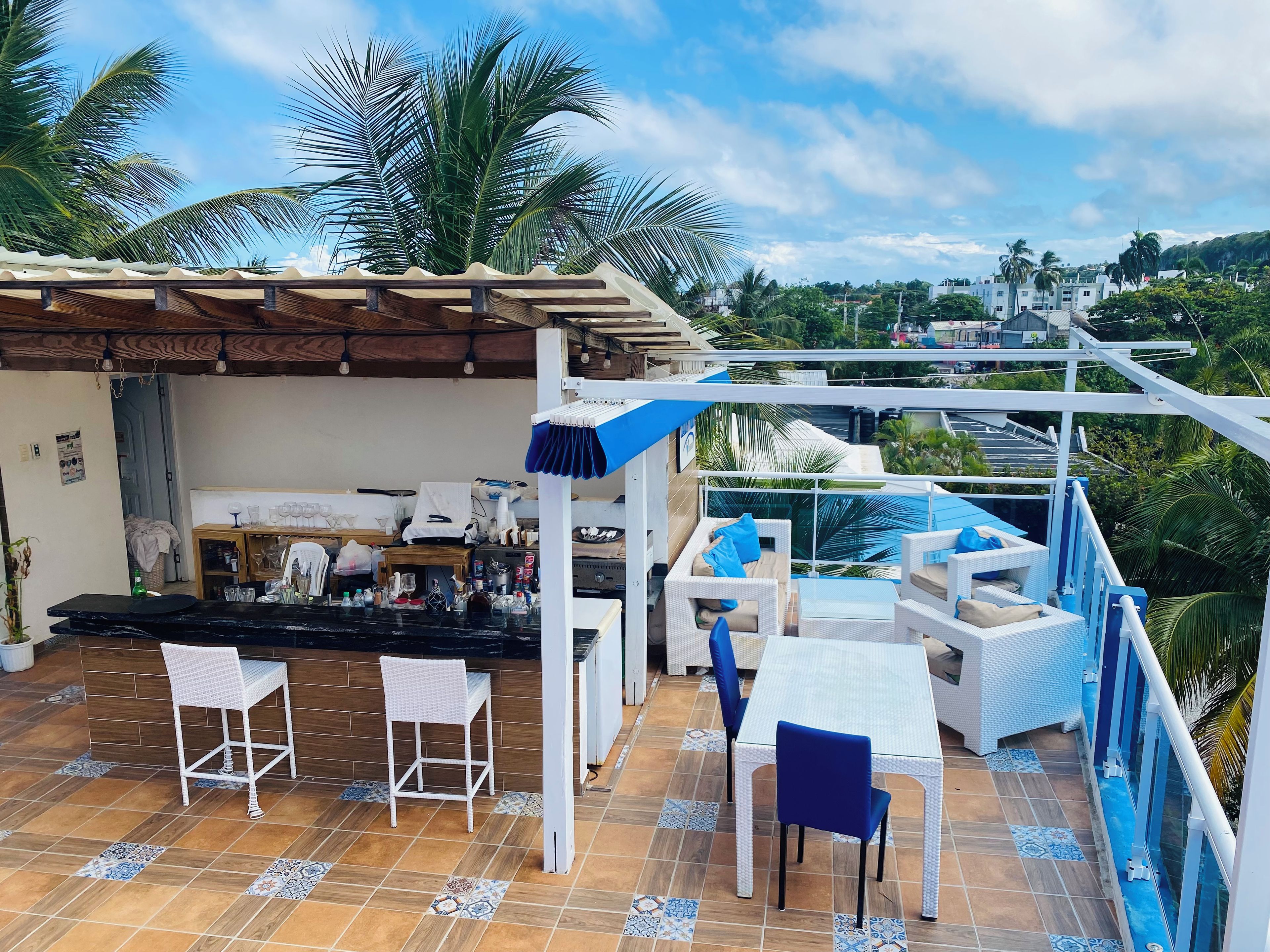 Un bar en la azotea con mesas al aire libre, piscina y vistas a la ciudad.