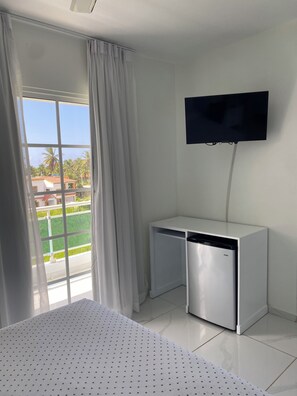 A hotel room with a bed, a TV mounted on the wall, and a window with curtains.