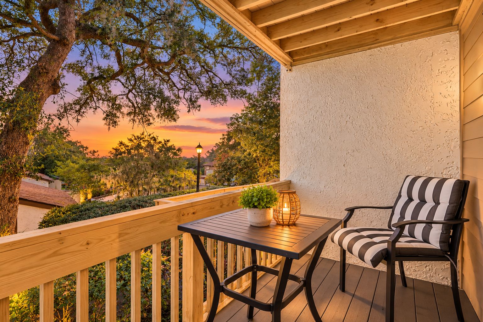 A wooden deck with a table and chair, a potted plant, and a lantern.
