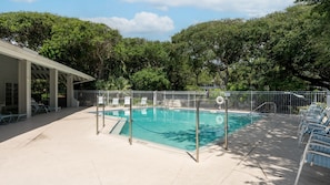A swimming pool with a fenced deck area, lounge chairs, and a covered seating area. - SW202 - Sea Woods Retreat | Walk to Beach + Pools & Trails (New Smyrna Beach)