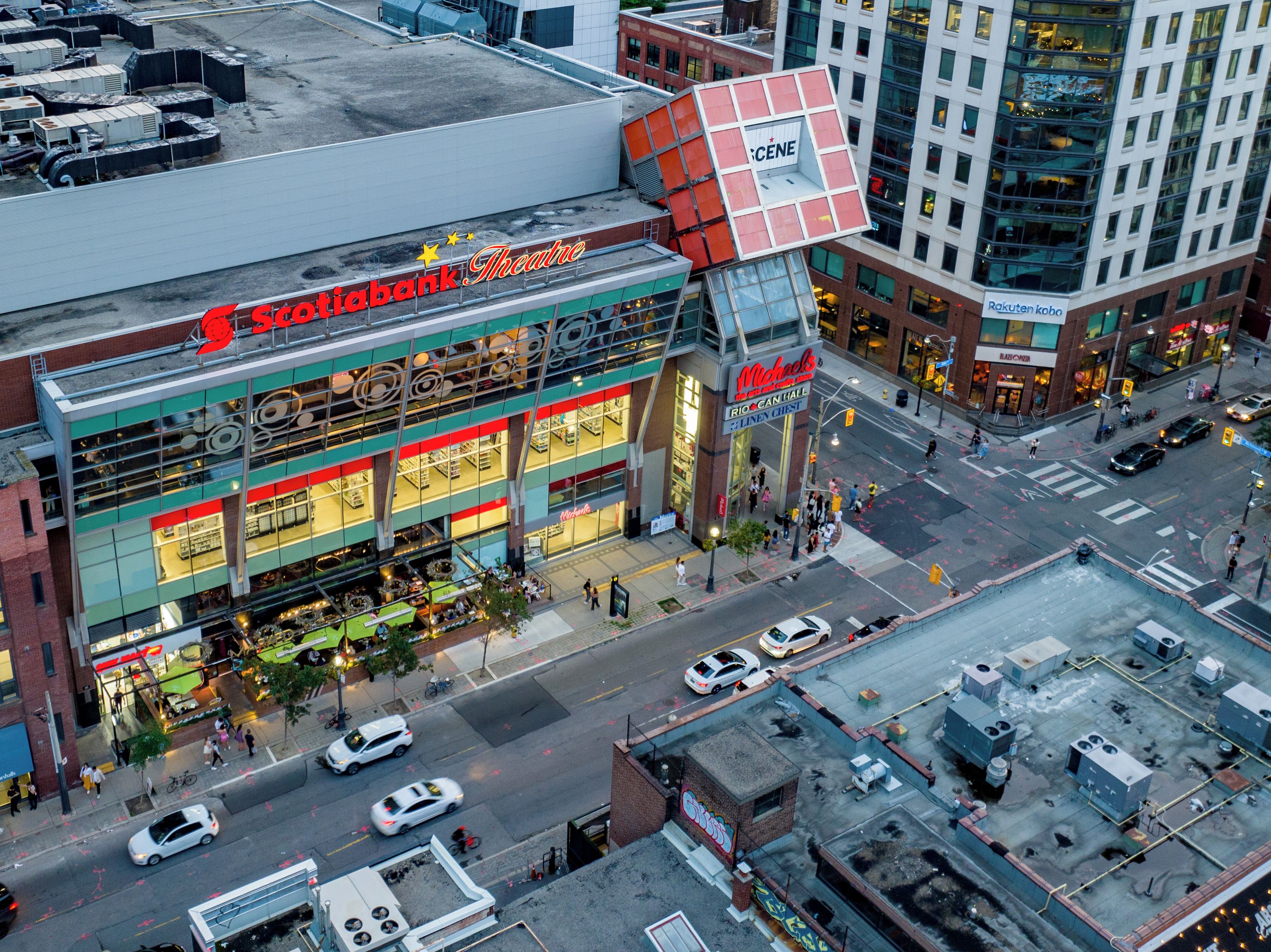 A multi-story building with a prominent 'Theater' sign, a 'Michael's' store, and a 'Rakuten Kobo' bookstore.