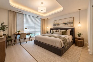 A modern bedroom with a large bed, bedside tables, a desk, and a chair.