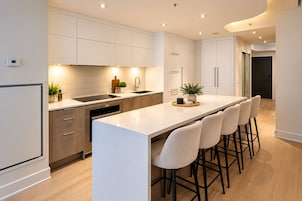 Una cocina moderna con una isla central, taburetes de bar y electrodomésticos integrados.