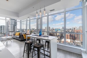 Una cocina moderna con una isla grande, taburetes de bar y vistas a la ciudad a través de amplias ventanas.