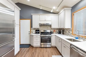 Una cocina moderna con electrodomésticos de acero inoxidable, armarios blancos y salpicadero de azulejos.
