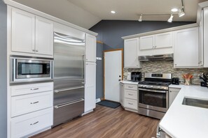 A modern kitchen with stainless steel appliances, white cabinetry, and a wood floor. - Your Home Away From Home! Only 20-25 Minutes to Madison! (Stoughton)