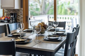 A dining table set with plates, glasses, and cutlery, with a view of greenery outside. - Your Home Away From Home! Only 20-25 Minutes to Madison! (Stoughton)