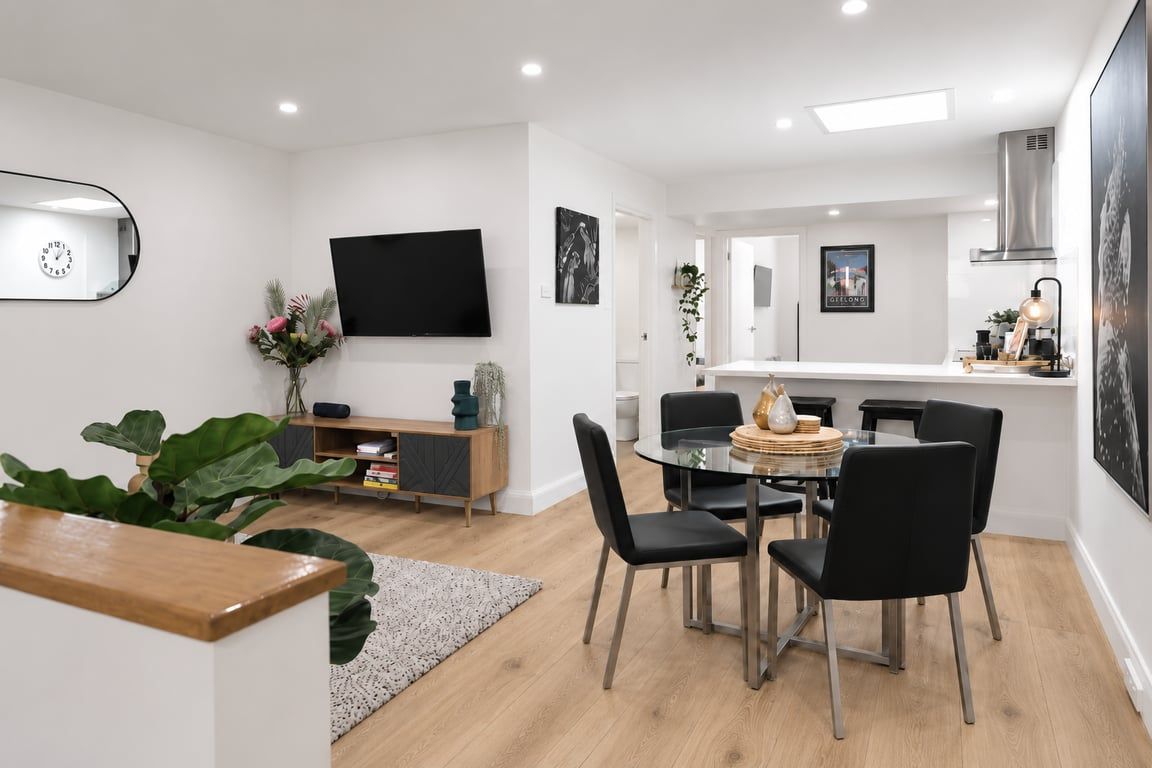 Una cocina moderna con comedor, un televisor de pantalla plana montado en la pared y un espejo grande.