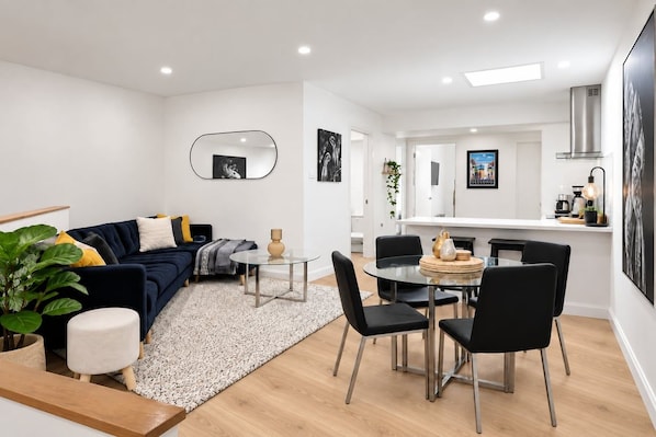 Ein modernes Wohnzimmer mit einer Couch, einem Couchtisch und einem Essbereich mit Stühlen.