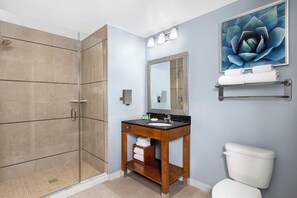 Ein Badezimmer mit einer gläsernen Duschkabine, einem Holzbadezimmer-Möbelstück, einem großen Spiegel und einer Toilette.