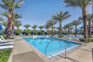 Un espace piscine avec des chaises longues et des palmiers.