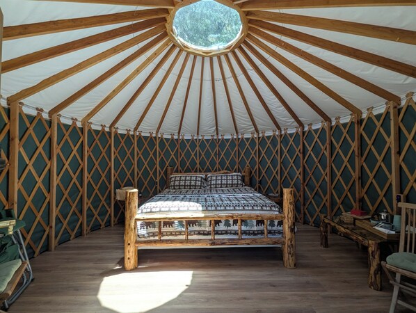 A yurt with a wooden bed, a circular skylight, and a lattice wall. - Big Woods Retreat (Miramonte)