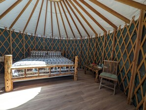 A yurt interior with a bed, wooden furniture, and a lattice wall. - Big Woods Retreat (Miramonte)