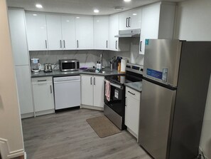 Una cocina moderna con armarios blancos, electrodomésticos de acero inoxidable y encimera negra.