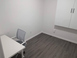 A room with a white desk, a mesh office chair, and a white cabinet with two doors. - Beautiful Tranquil 1bedroom Basement Suite (Beaumont)