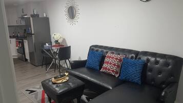 Un salon avec un canapé en cuir noir, une table basse et une horloge murale.