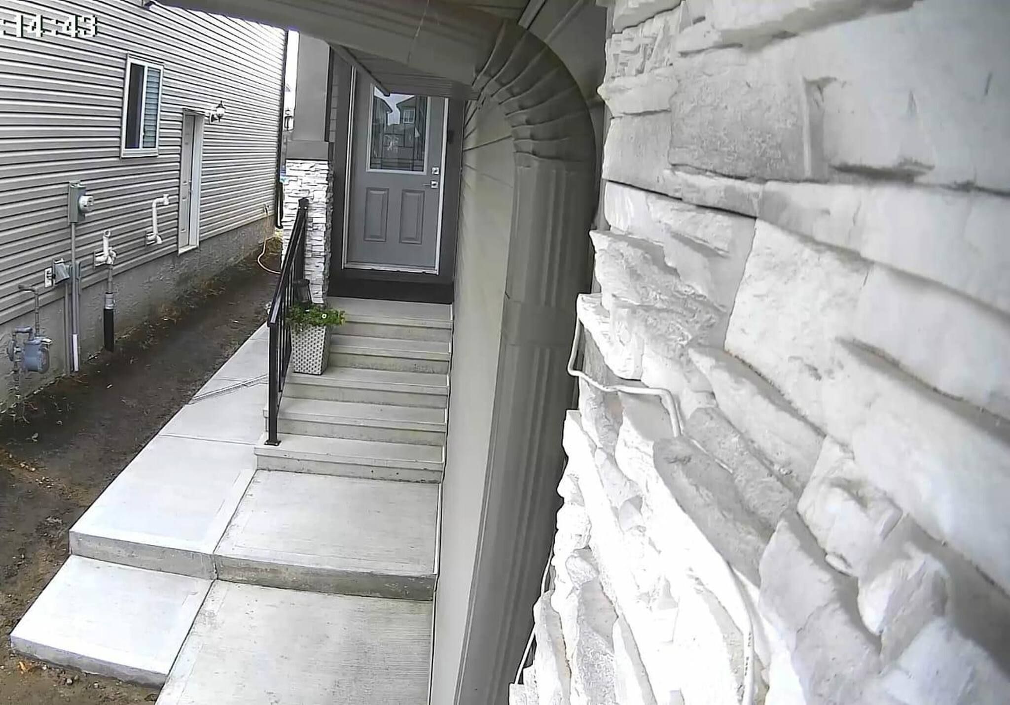 Una vivienda con fachada de piedra, una puerta principal y un pequeño jardín delantero.
