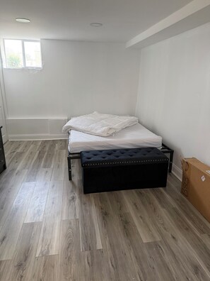 Een slaapkamer met een bed, een zwarte bekleden bank en een raam.