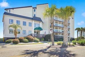A multi-story hotel with a covered entrance and a palm tree in the foreground. - A Place at the Beach - Windy Hill 308 - 2BR 2BA Condo North Myrtle Beach Pool & Hot tub (North Myrtle Beach)