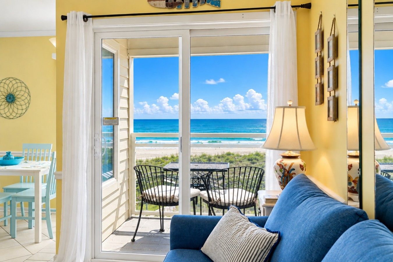 Expansive patio windows showcase sweeping seaside scenery and sandy dunes, while a charming outdoor café setting invites peaceful mornings and relaxing evening refreshments.