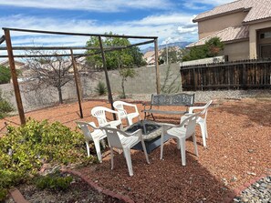 A patio area with a pergola, white plastic chairs, a fire pit, and a view of a residential neighborhood. - Fantastic 5-bedroom family house with AC in vibrant Albuquerque (Albuquerque)